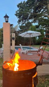 a fire pit with an umbrella next to a pool at Lazlo in Sierra de los Padres