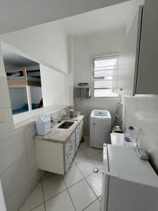 a white kitchen with a sink and a toilet at CARIBONI in Guarujá