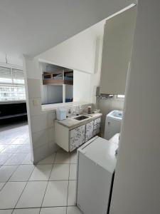 a white kitchen with a sink and a refrigerator at CARIBONI in Guarujá