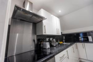 a kitchen with white cabinets and a stainless steel refrigerator at Cosy Hideaway Close to Town in Reading