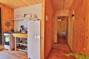 a kitchen with a white refrigerator and wooden walls at Pousada Refúgio Araçá in Morro Redondo
