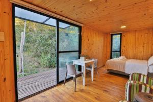 a bedroom with a bed and a table and a window at Pousada Refúgio Araçá in Morro Redondo