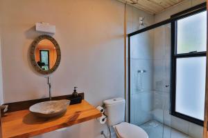 a bathroom with a sink and a toilet and a mirror at Pousada Refúgio Araçá in Morro Redondo