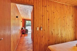 a room with wooden walls and a hallway with a bed at Pousada Refúgio Araçá in Morro Redondo
