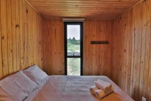 a wooden room with a bed with a window at Pousada Refúgio Araçá in Morro Redondo