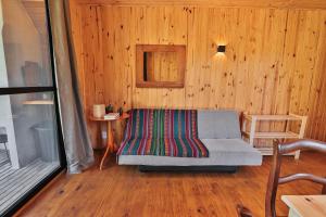 a living room with a couch in a wooden wall at Pousada Refúgio Araçá in Morro Redondo
