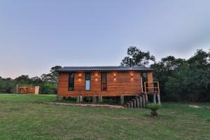 a log cabin in a field with trees in the background at Pousada Refúgio Araçá in Morro Redondo