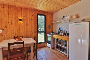 a kitchen with a table and a white refrigerator at Pousada Refúgio Araçá in Morro Redondo