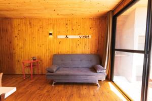 a couch in the corner of a room with wooden walls at Pousada Refúgio Araçá in Morro Redondo