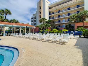 uma fila de cadeiras e uma piscina em frente a um hotel em Spacious condo with balcony overlooking the natural preserve OW10-307 em New Smyrna Beach