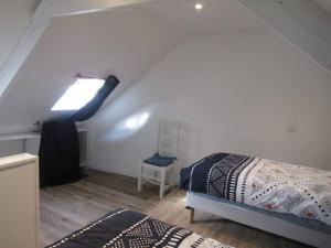 Cette chambre mansardée comprend un lit et une fenêtre. dans l'établissement Ti an traõn le petit gîte en cœur de Bretagne, à Carhaix-Plouguer