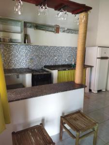 a kitchen with a counter and two wooden stools at Casa da Drica Trancoso in Trancoso