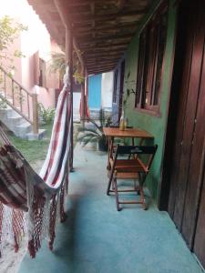 a porch with a hammock and a table on a house at Casa da Drica Trancoso in Trancoso