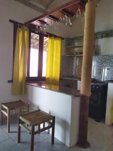 a kitchen with yellow curtains and a counter with a stool at Casa da Drica Trancoso in Trancoso