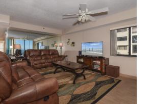 a living room with brown leather furniture and a flat screen tv at Floor-to-Ceiling Oceanfront Views ~ Chadham-by-the-Sea 315 in New Smyrna Beach