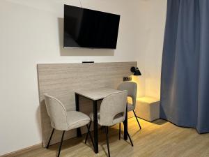 una mesa y sillas con TV en la pared en Apartimo München-Unterhaching, en Unterhaching
