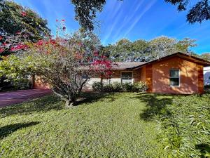 a house with a tree in the yard at Cozy home with 1-car garage within walking distance to the beach. 836C in New Smyrna Beach
