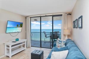 a living room with a blue couch and a view of the ocean at Beachfront 2 Bed at Popular Seawinds!!! in Marco Island
