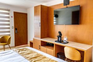 a room with a bed and a desk with a television at Hotel 5 Inn Select in Rancho de la Cruz