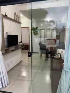 uma sala de estar com uma televisão e uma porta de vidro em Aconchegante Casa de praia em Matinhos