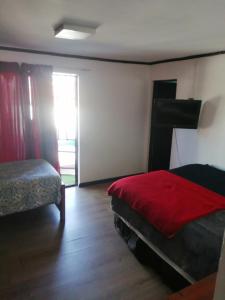 1 dormitorio con 1 cama con manta roja en Coco Cris Hostal en Coquimbo
