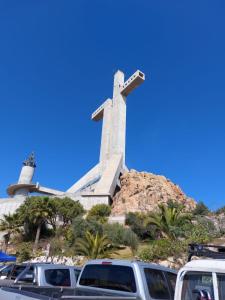 una cruz en la cima de una colina con coches aparcados delante en Coco Cris Hostal en Coquimbo