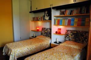 two beds in a room with bookshelves and lamps at Aurum B&B in San Giovanni Teatino
