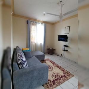 ein Wohnzimmer mit einem blauen Sofa und einem TV in der Unterkunft Oasis Apartments in Mombasa