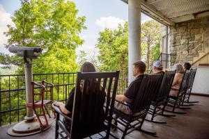 um grupo de pessoas sentadas em cadeiras de balanço em um alpendre em 1886 Crescent Hotel and Spa em Eureka Springs