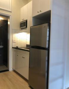 a kitchen with a stainless steel refrigerator and white cabinets at Elegant 1BR Apartment in NYC! in New York