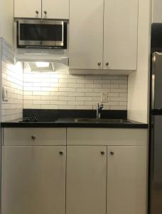 Elegant 1BR Apartment in NYC! في نيويورك: مطبخ بدولاب بيضاء ومغسلة وميكروويف