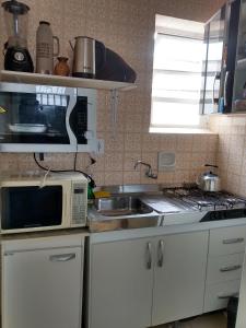 una pequeña cocina con microondas y fregadero en Apto Central Barra de Imbé, en Imbé