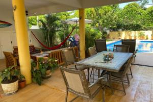 eine Terrasse mit einem Tisch, Stühlen und einem Pool in der Unterkunft Zandoyo Bed & Breakfast in Puerto Escondido