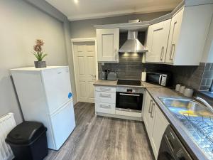 eine Küche mit weißen Schränken und einem weißen Kühlschrank in der Unterkunft Seaviews Apartment 2, Whitley Bay Sea Front in Whitley Bay