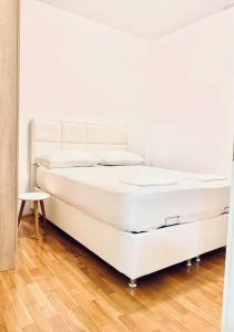 a white bed in a room with a wooden floor at Monte Star apartments in Budva
