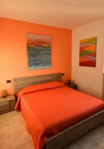 a bedroom with an orange bed and two paintings at Le Palme Sona in Sona