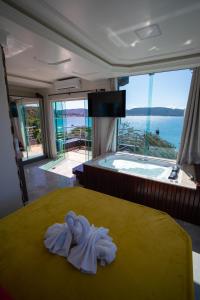 a room with a bed with a tub and towels at Pousada Mirante do César in Bombinhas