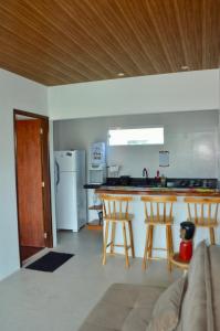 a kitchen with a counter and two bar stools at Vila Las Hermanas in Pôrto de Pedras