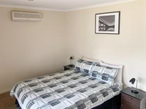 a bedroom with a bed with a plaid comforter at Eildon Views in Bonnie Doon