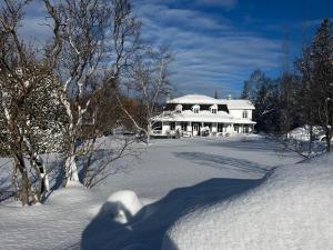 een sneeuwbedekte tuin met een groot wit huis bij Auberge musicale Pour un Instant in La Malbaie