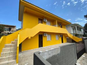 a yellow house with stairs in front of it at Apartamento cachoeira in Florianópolis