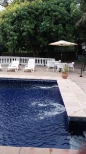 una piscina con sillas blancas y sombrilla en Lasuiza Suites, en San Bernardino
