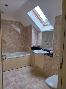 a bathroom with a tub and a sink and a skylight at Beautiful Holiday Cottage near Kenmare in Kenmare