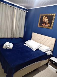 a blue bedroom with a bed with a blue wall at Hospedagem D´Roos in Canela
