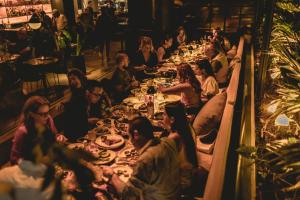 un gruppo di persone seduti a tavoli lunghi in un ristorante di Urbanica Euclid a Miami Beach