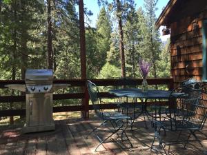 einen Tisch und Stühle auf einer Terrasse mit Grill in der Unterkunft Ahwahnee-be Vintage Cabin - Walk to town! in Idyllwild