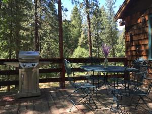 ein Tisch und Stühle auf einer Terrasse mit Grill in der Unterkunft Ahwahnee-be Vintage Cabin - Walk to town! in Idyllwild