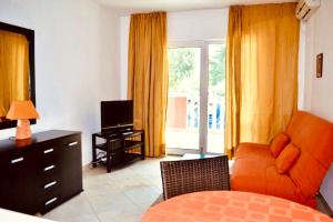 a living room with an orange couch and a television at Monte Star apartments in Budva