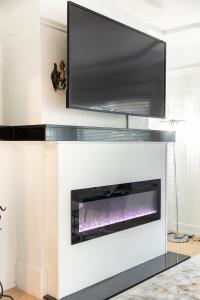 a fireplace with a flat screen tv above it at Cityscape Haven - Central SF Home near SFO in San Bruno +19 photos