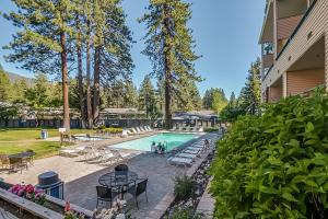 a swimming pool with tables and chairs and trees at Lakeland Village South Lake Tahoe in South Lake Tahoe